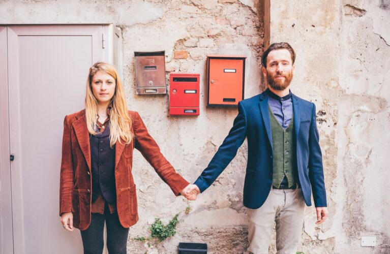 Young couple in love holding hands standing front door